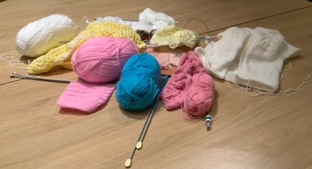 4 balls of wool, white yellow pink and blue with needles 